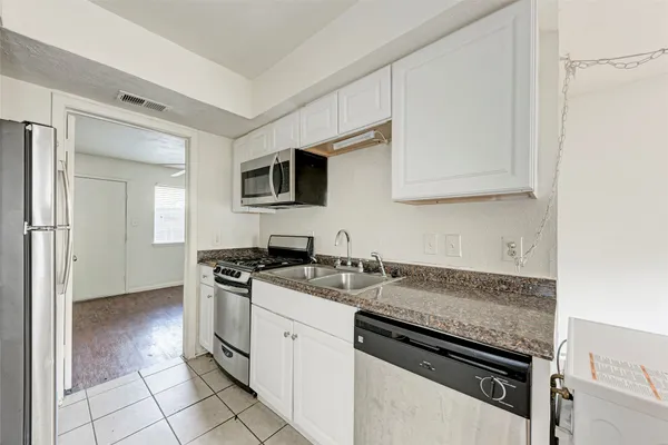 a kitchen with granite countertop a sink stove and cabinets