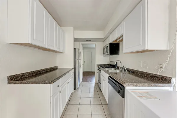 a kitchen with granite countertop a refrigerator and white cabinets