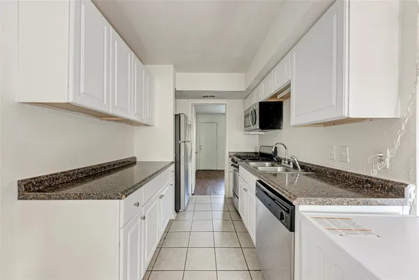 a kitchen with granite countertop a sink stove and cabinets