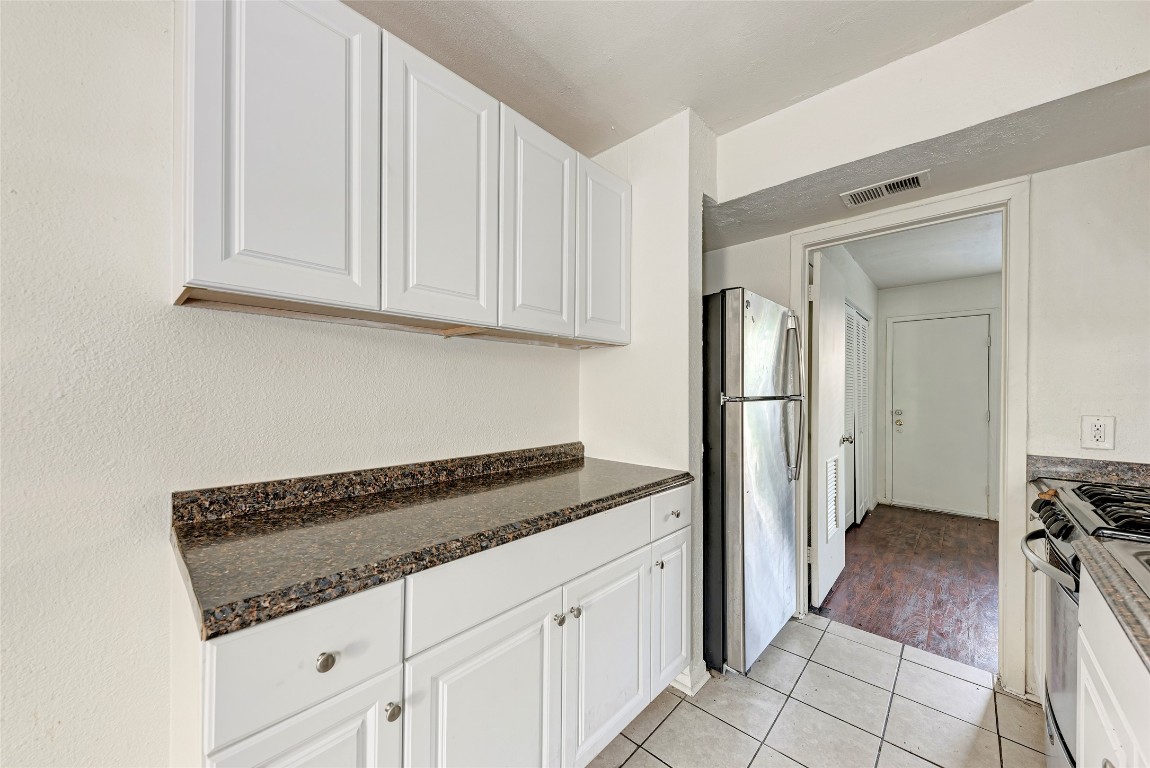 1010 West 23rd Street, Unit 5 Austin, TX 78705 - Photo 7 of 10 a kitchen with granite countertop a refrigerator and white cabinets