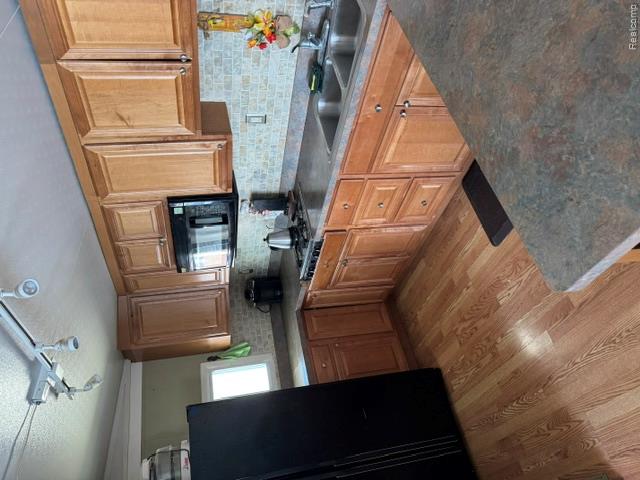 10001 Goodall Road, Unit 404 Durand, MI 48429 - Photo 15 of 50 Kitchen featuring black appliances, track lighting, wood finish cabinetry, light wood-style floors, and backsplash