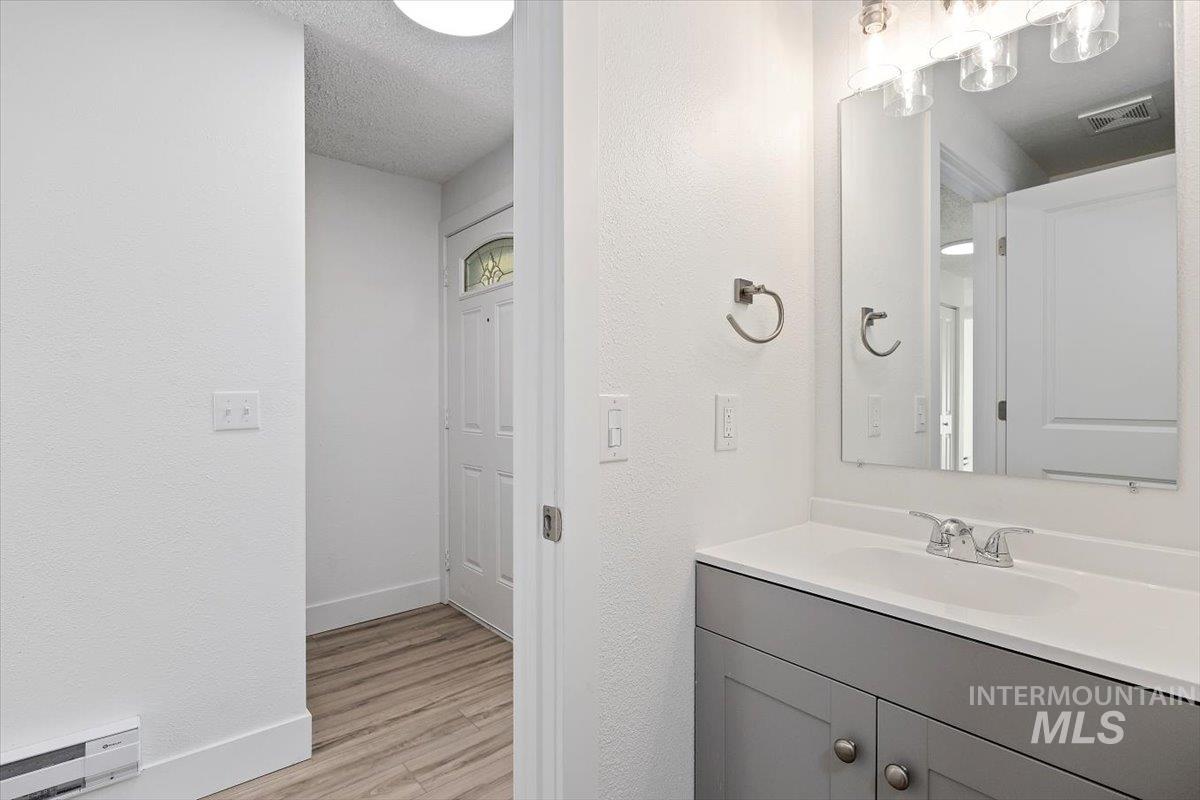 259 Pheasant Road West, Unit 3 Twin Falls, ID 83301 - Photo 12 of 24 Bathroom featuring vanity, a baseboard radiator, a textured wall, light wood finished floors, and a textured ceiling