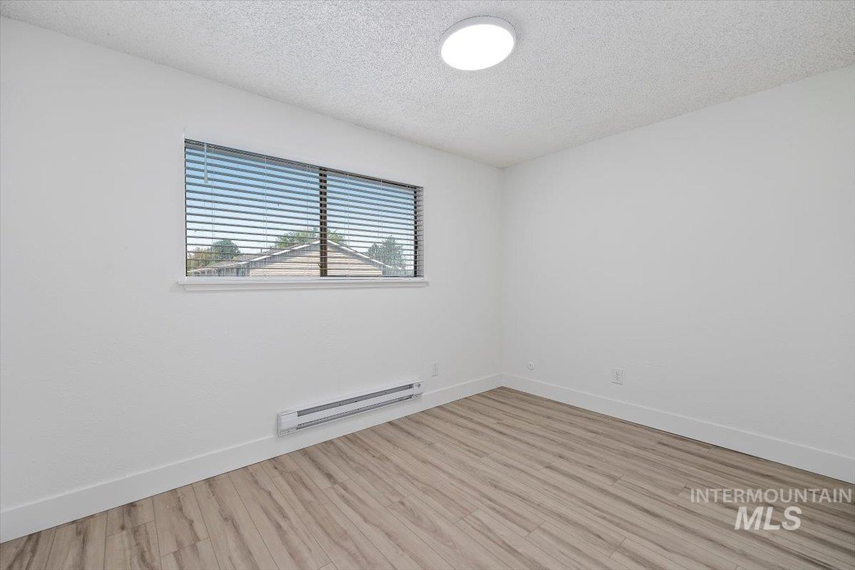 259 Pheasant Road West, Unit 3 Twin Falls, ID 83301 - Photo 16 of 24 Empty room featuring a textured ceiling, a baseboard radiator, and wood finished floors