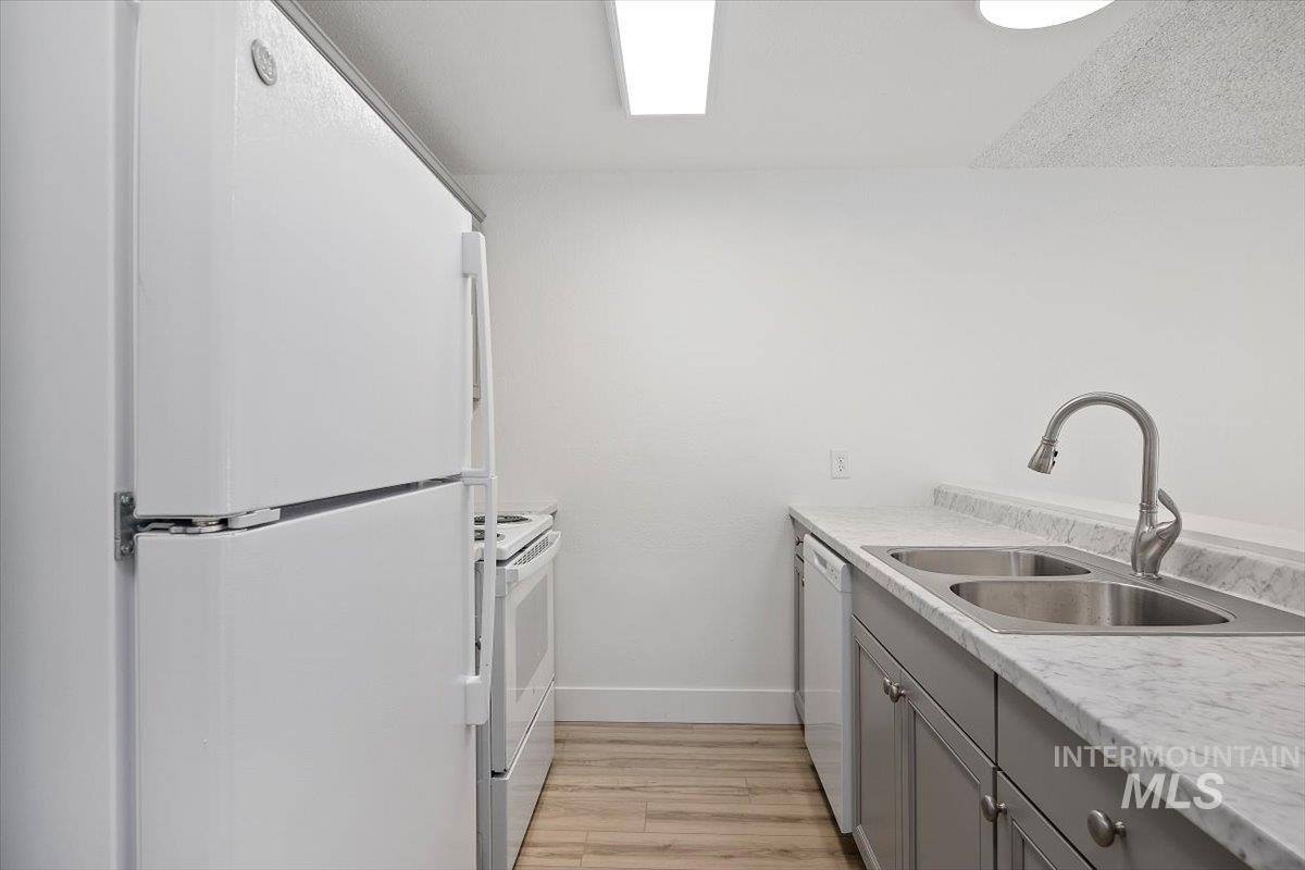 259 Pheasant Road West, Unit 3 Twin Falls, ID 83301 - Photo 10 of 24 Kitchen with gray cabinetry, white appliances, light countertops, and light wood-style floors