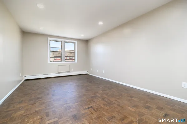 an empty room with wooden floor and window