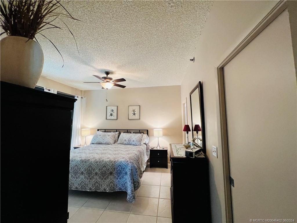 221 Northeast Plantation Road, Unit 215 Stuart, FL 34996 - Photo 25 of 83 a bedroom with a bed and a chandelier