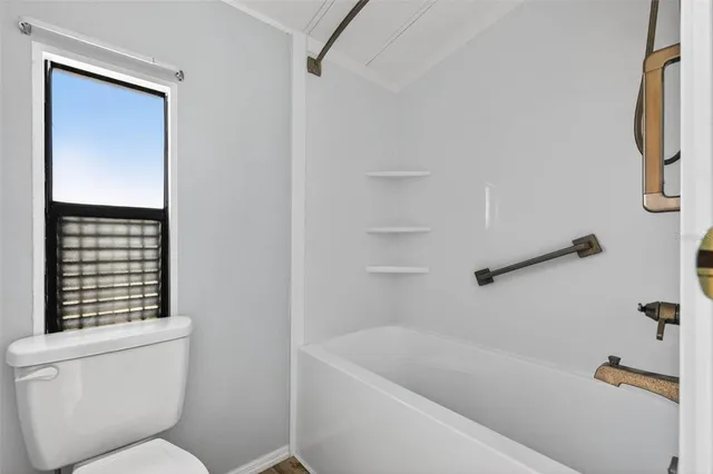 a bathroom with a tub a toilet and a window