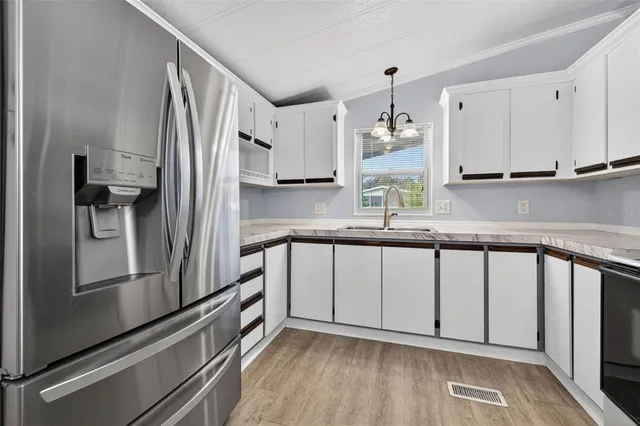 a kitchen with stainless steel appliances granite countertop a refrigerator a sink and white cabinets