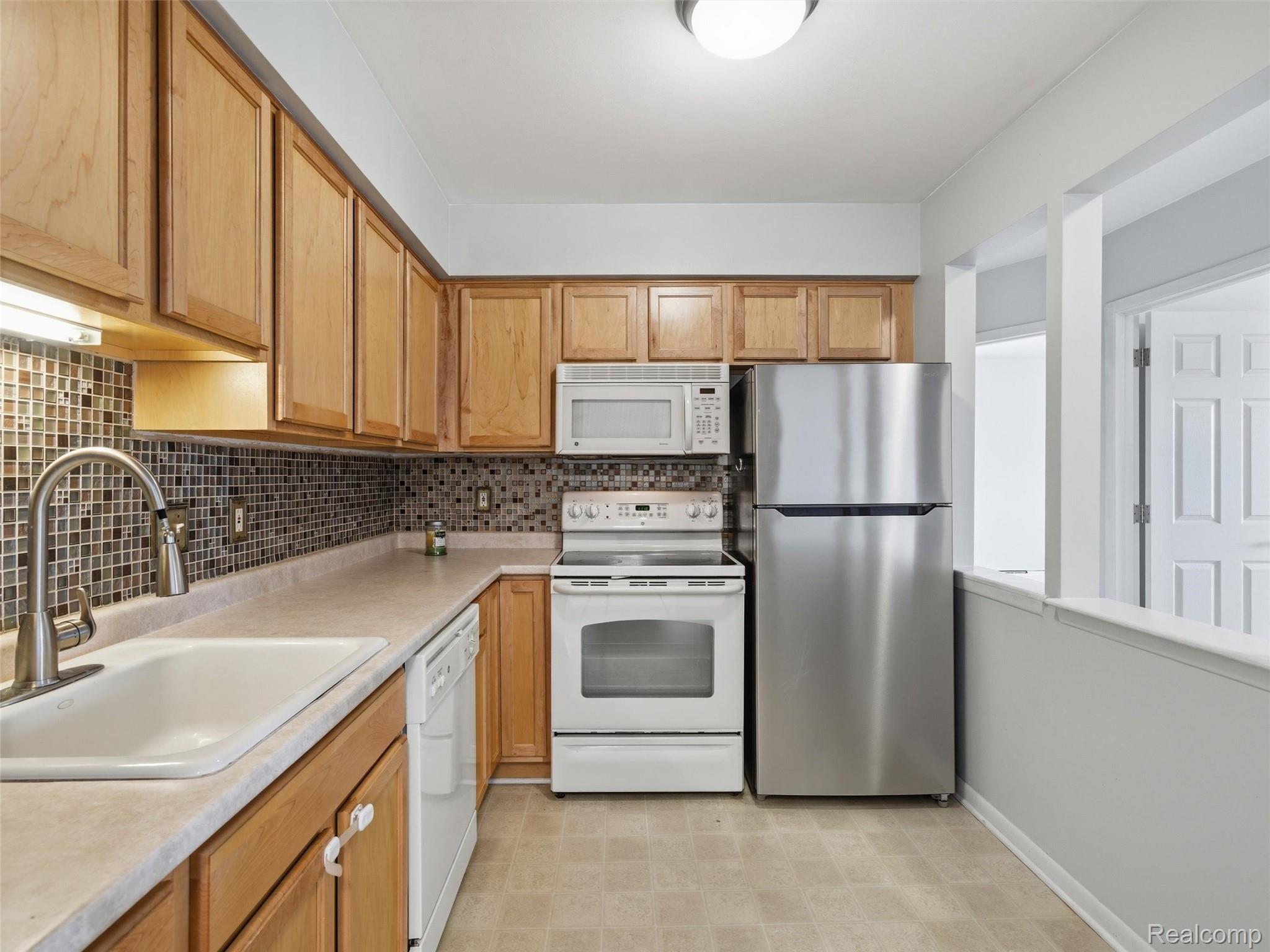 475 Baldwin Avenue, Unit 26 Rochester, MI 48307 - Photo 6 of 19 Kitchen featuring white appliances, light countertops, backsplash, light floors, and wood finish cabinetry