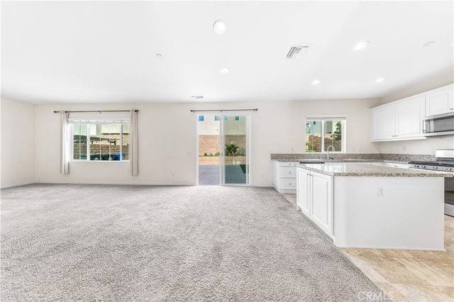 a large white kitchen with kitchen island a sink stainless steel appliances and cabinets