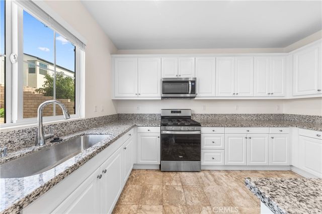 a kitchen with stainless steel appliances granite countertop a sink stove and cabinets