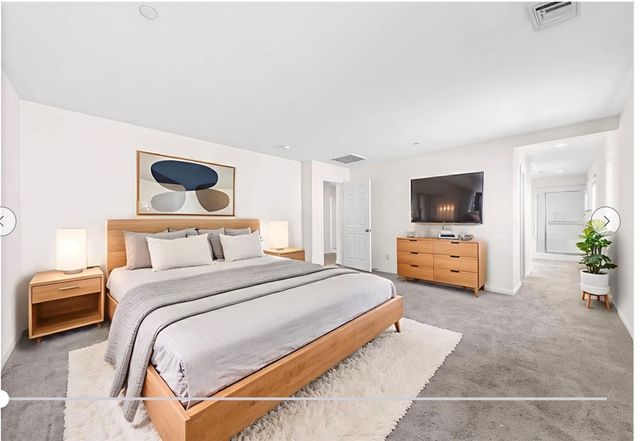 a view of a hallway with wooden floor and a bathroom