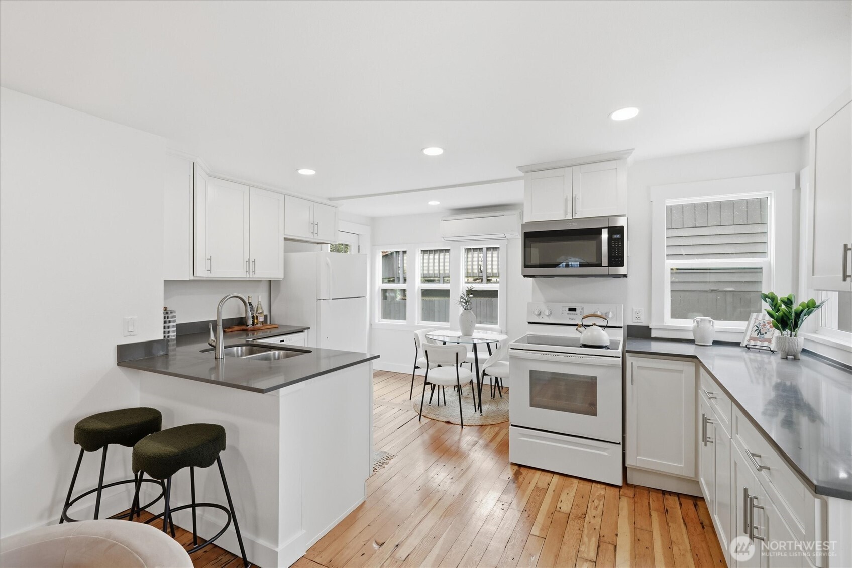 1651 Southwest 114th Street Seattle, WA 98146 - Photo 12 of 37 a kitchen with granite countertop a stove top oven a sink dishwasher a dining table and chairs with wooden floor