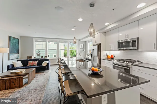 a kitchen with stainless steel appliances granite countertop a refrigerator a stove a sink a dining table and chairs with wooden floor