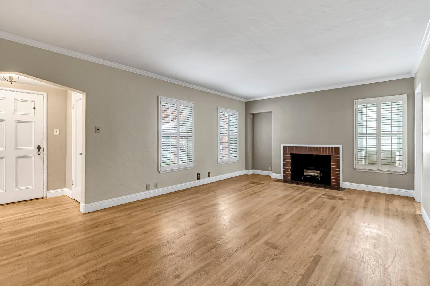 215 East Clinton Avenue Fresno, CA 93704 - Photo 6 of 29 a view of an empty room with wooden floor fireplace and a window