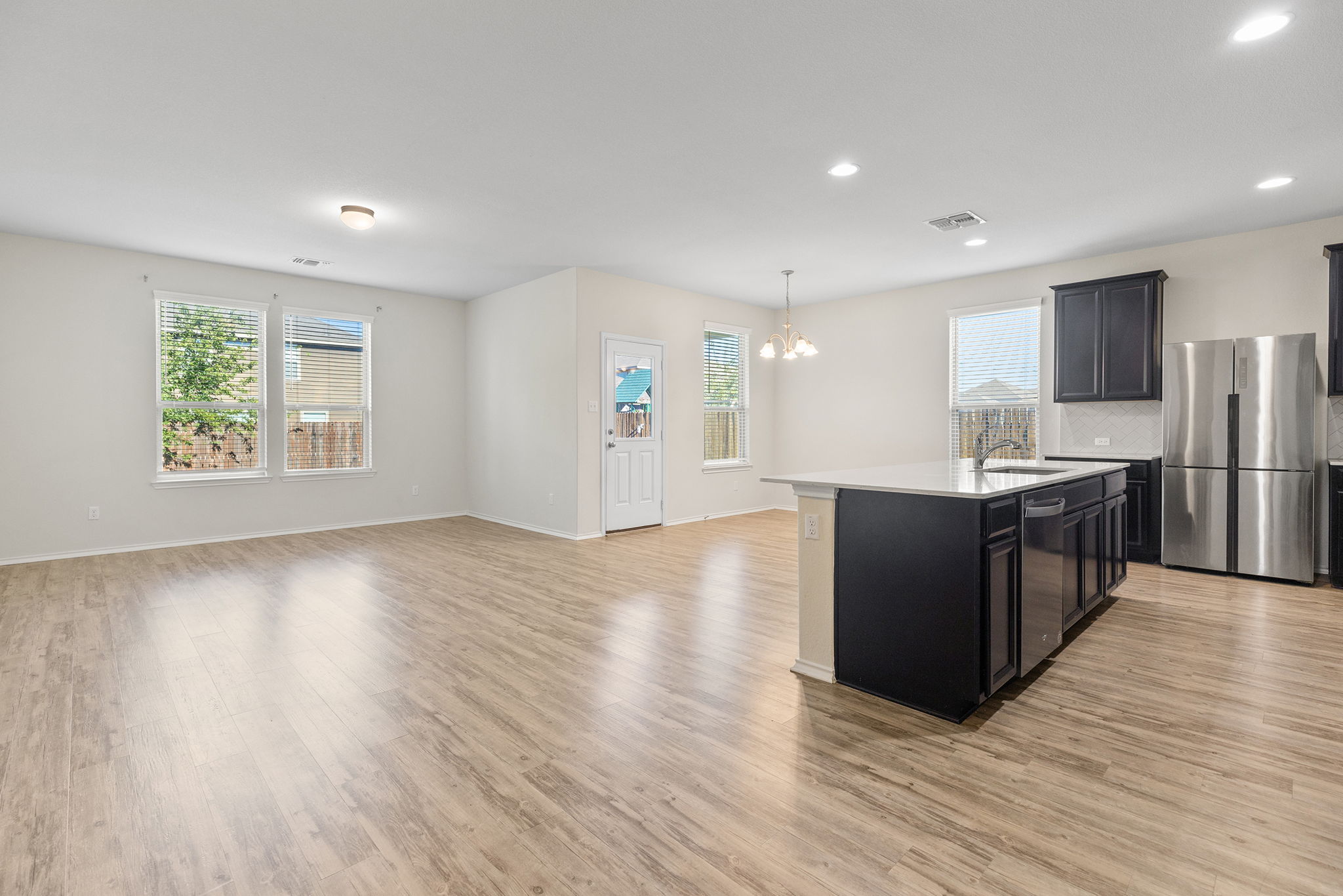 332 Spotted Rail Ridge Leander, TX 78641 - Photo 38 of 38 Kitchen with a center island with sink, appliances with stainless steel finishes, pendant lighting, open floor plan, and light wood-type flooring