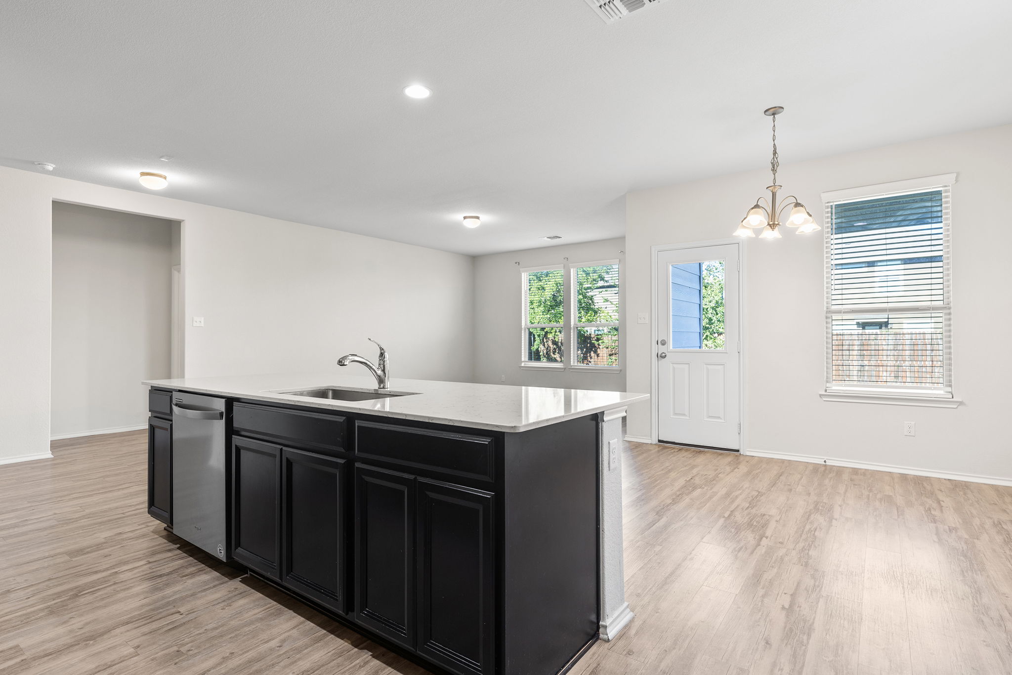 332 Spotted Rail Ridge Leander, TX 78641 - Photo 9 of 38 Kitchen with dark cabinetry, hanging light fixtures, a center island with sink, light wood-style floors, and recessed lighting