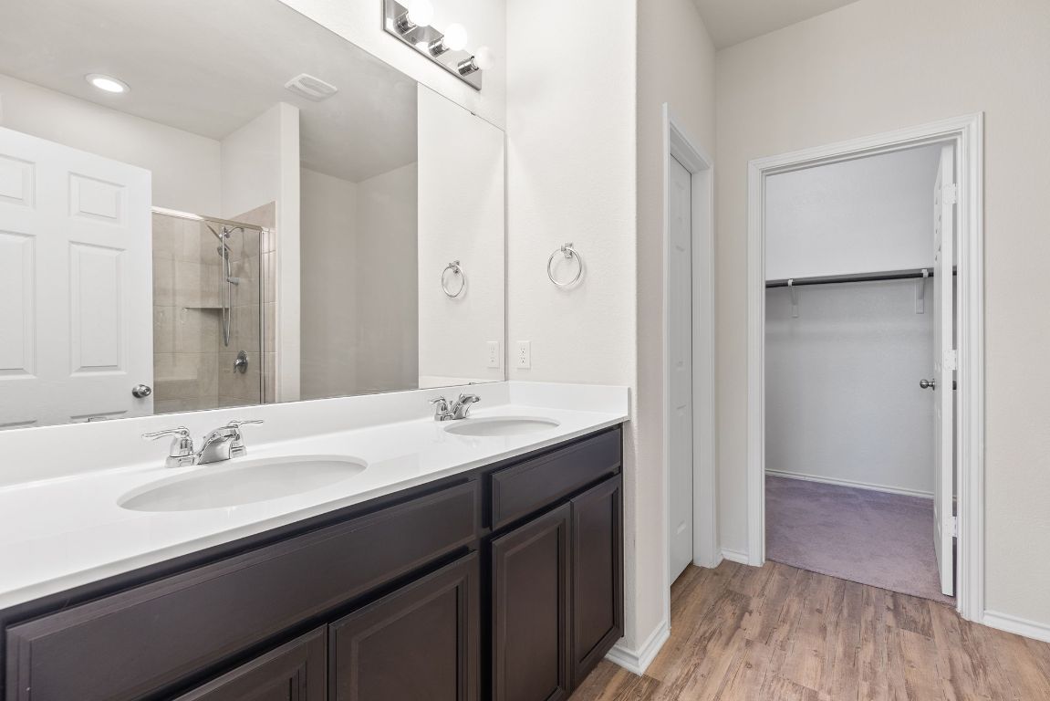 332 Spotted Rail Ridge Leander, TX 78641 - Photo 13 of 35 Primary bathroom featuring a stall shower, light wood-style floors, double vanity, and a spacious closet