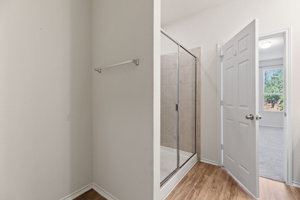 332 Spotted Rail Ridge Leander, TX 78641 - Photo 14 of 35 Primary bathroom featuring a stall shower and wood finished floors