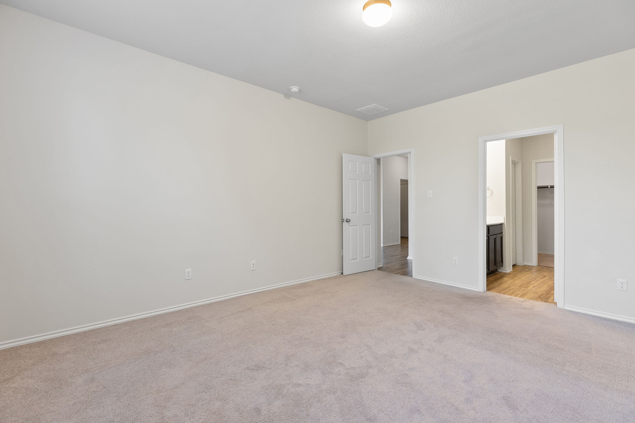 332 Spotted Rail Ridge Leander, TX 78641 - Photo 16 of 38 Main floor primary bedroom #1 with light colored carpet and ensuite bath