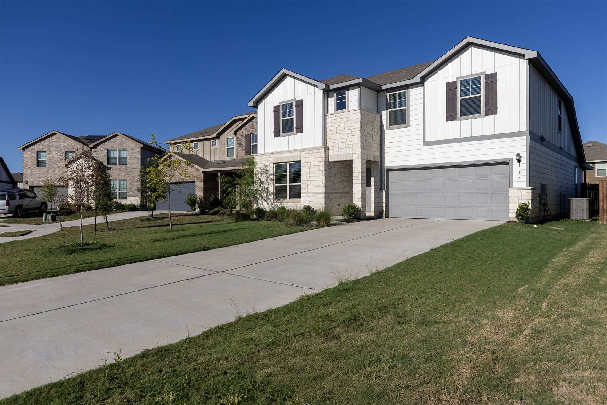 332 Spotted Rail Ridge Leander, TX 78641 - Photo 34 of 38 Modern farmhouse style home featuring board and batten siding, a front lawn, concrete driveway, a garage, and stone siding