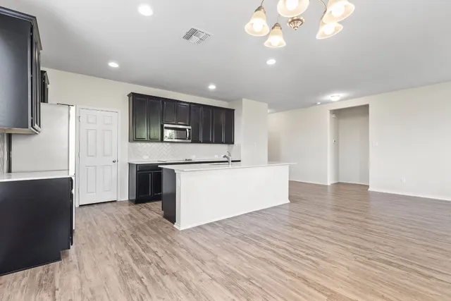 a large kitchen with stainless steel appliances a large counter top a stove a sink and a refrigerator