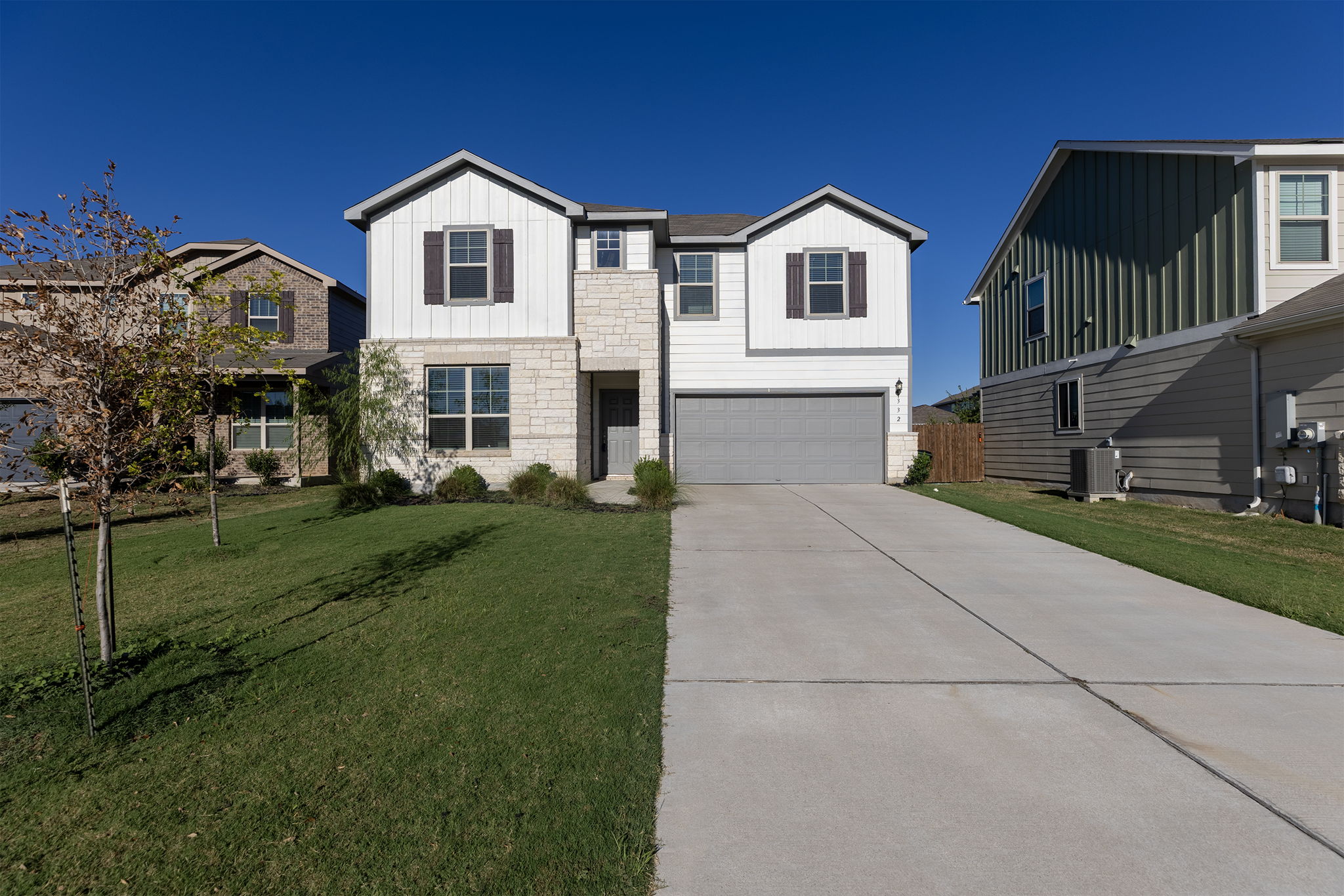 332 Spotted Rail Ridge Leander, TX 78641 - Photo 6 of 38 View of front of home with board and batten siding, concrete driveway, a front yard, and stone siding