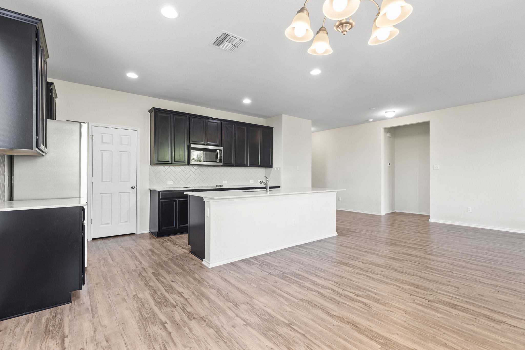 332 Spotted Rail Ridge Leander, TX 78641 - Photo 7 of 38 Kitchen with tasteful backsplash, hanging light fixtures, light wood-style floors, dark cabinets, and a chandelier