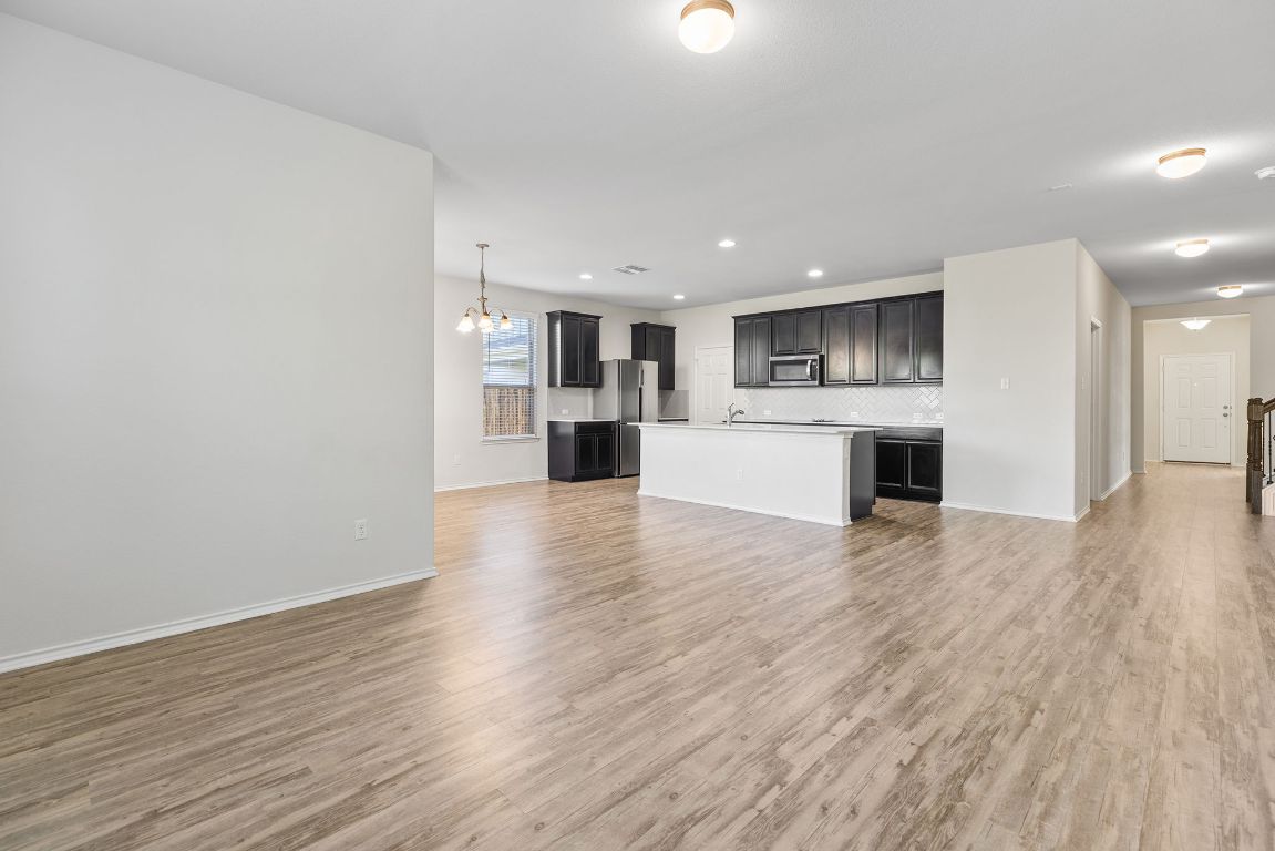 332 Spotted Rail Ridge Leander, TX 78641 - Photo 7 of 35 Unfurnished living room featuring a chandelier, light wood-style floors, and recessed lighting