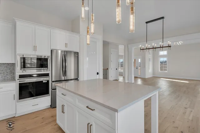 a kitchen with stainless steel appliances a refrigerator a sink a stove and white cabinets