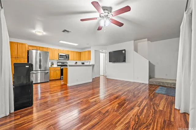 a view of a kitchen with a refrigerator a ceiling fan and wooden floor
