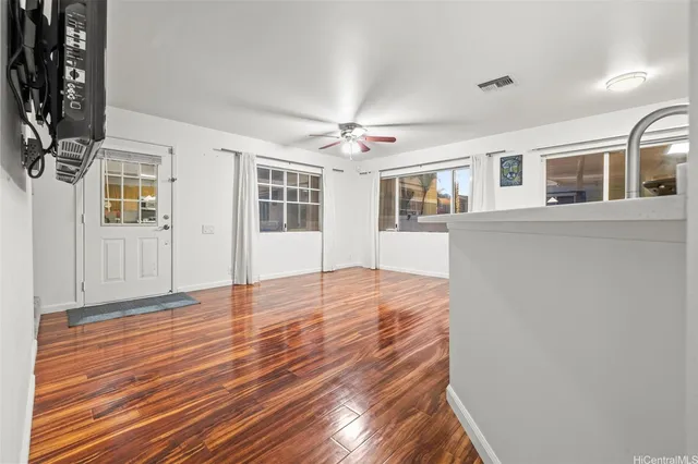 a view of empty room with wooden floor and fan