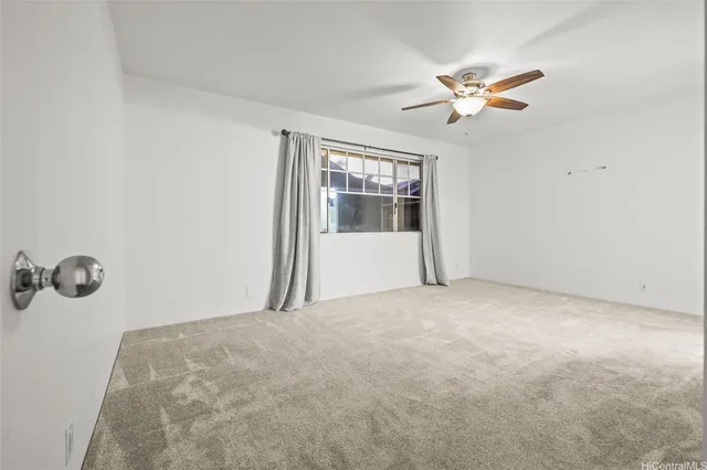 an empty room with ceiling fan and window
