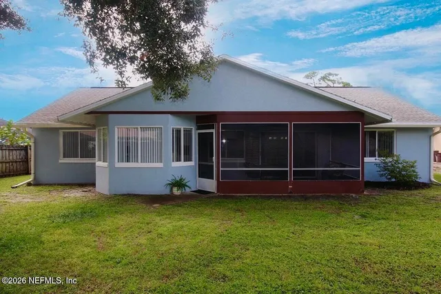 a view of a house with a yard and a large tree
