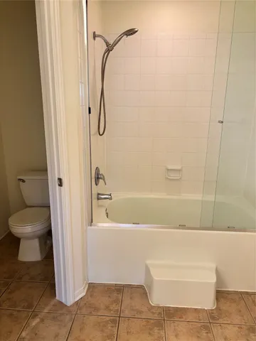 a bathroom with a granite countertop bathtub shower and toilet