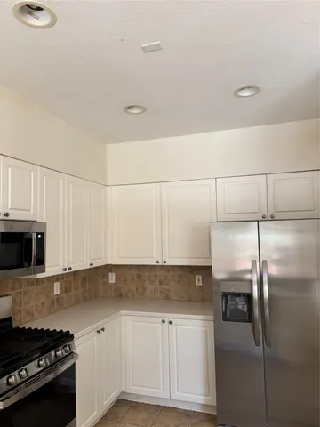 a kitchen with stainless steel appliances granite countertop a refrigerator a stove and white cabinets