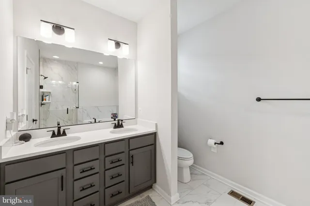 a bathroom with a double vanity sink toilet and a mirror