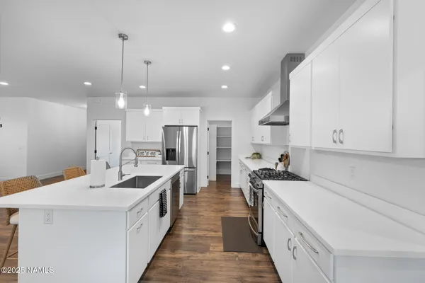 a large white kitchen with stainless steel appliances lots of counter space and a sink