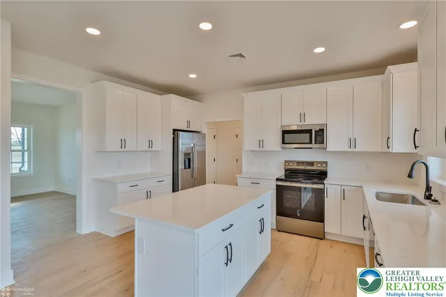 a kitchen with stainless steel appliances a sink a stove a refrigerator cabinets and a window