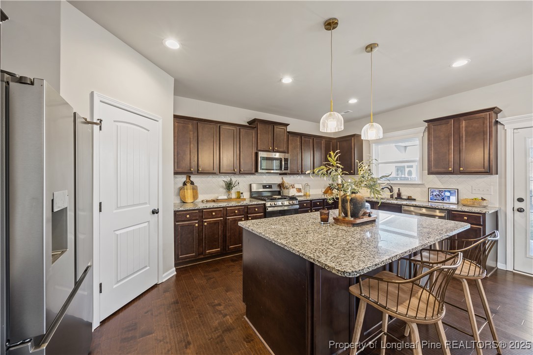 1709 Eagle Hill Road Fayetteville, NC 28312 - Photo 22 of 46 a kitchen with kitchen island granite countertop wooden cabinets a stove a counter space and stainless steel appliances