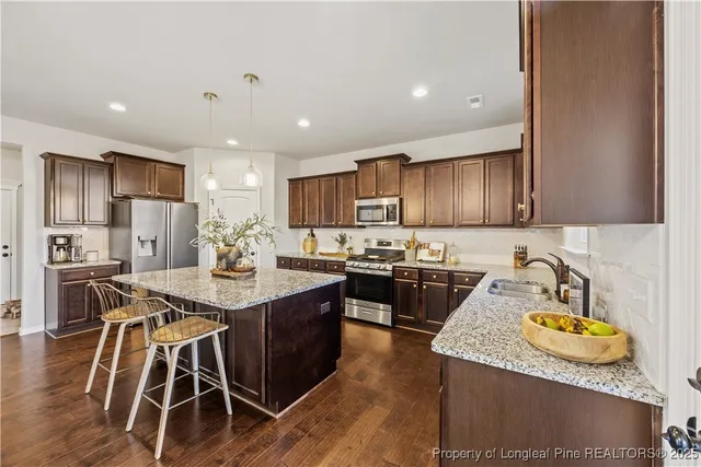 a kitchen with kitchen island granite countertop wooden floors and stainless steel appliances
