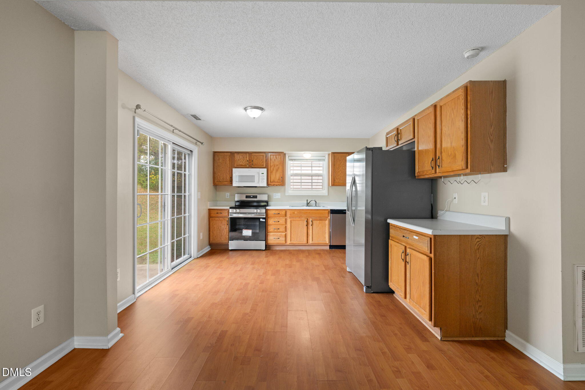4701 Tommans Trail Raleigh, NC 27616 - Photo 26 of 36 a kitchen with stainless steel appliances wooden floor and large windows