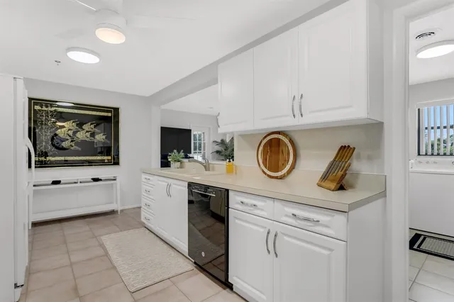 a view of cabinets a sink and a stove in a white room