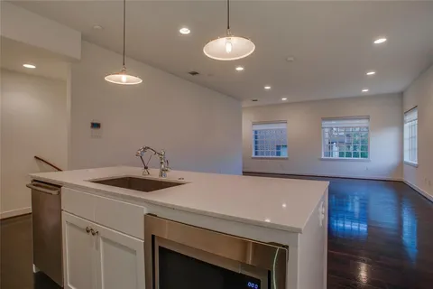 a kitchen with a sink chandelier and wooden floor