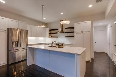 a kitchen with stainless steel appliances granite countertop a refrigerator a sink dishwasher a stove and a refrigerator with wooden floor