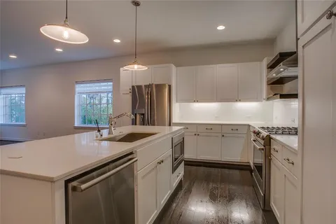 a kitchen with a sink stove and wooden floor