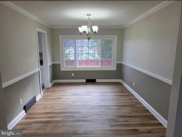 a view of an empty room with wooden floor fireplace and a window