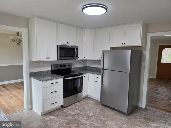 a kitchen with stainless steel appliances granite countertop a refrigerator a stove and a sink
