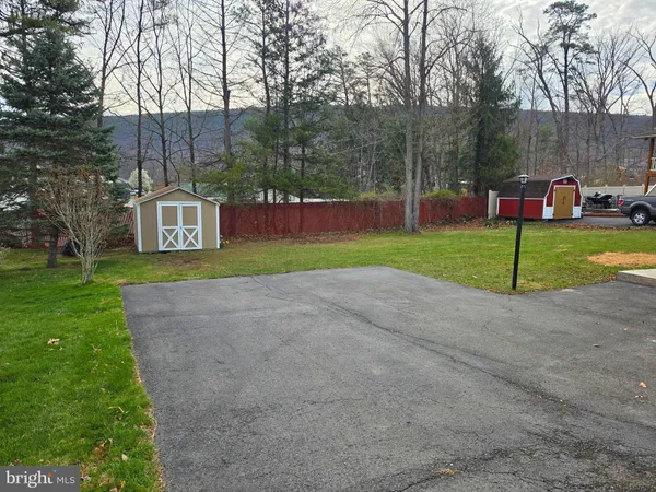 a view of an empty room with wooden floor fireplace and a window