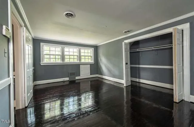 a view of an empty room with a window and wooden floor